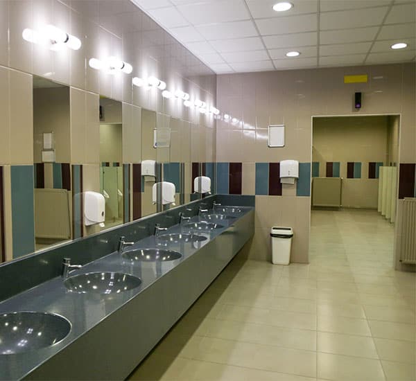 a plblic restroom with individual spattls and several sinks